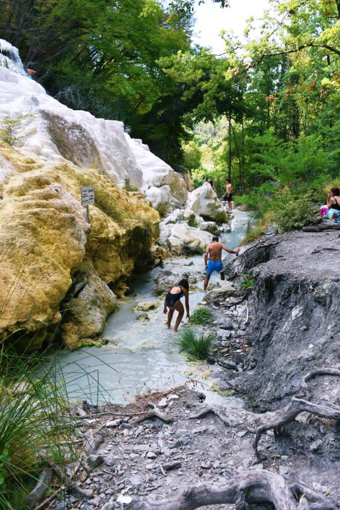 People walking in a stream of water flowing between stones